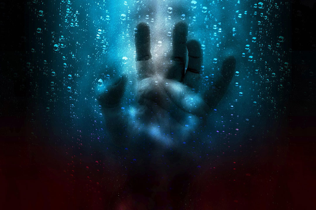 A hand floats in the ocean, representing the idea of horror.