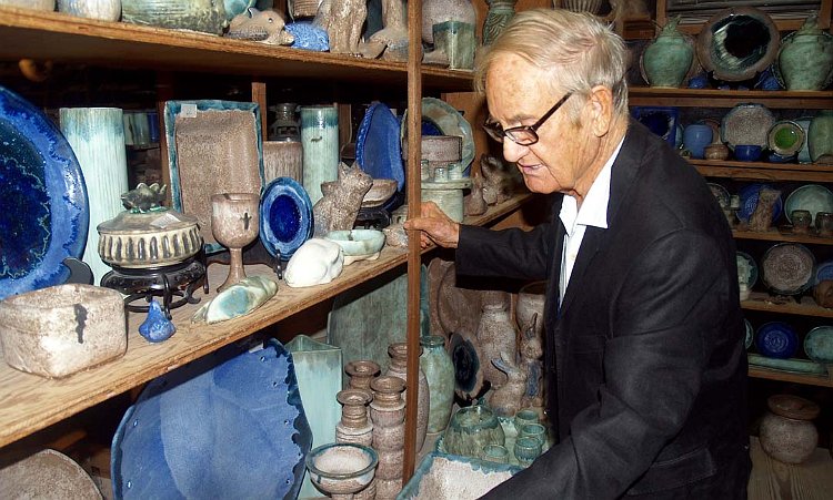 Lee McCarty, owner of McCartys Pottery in Merigold, stands in front of a wall of pottery.